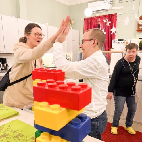 Ohjaaja ja asukas antavat ylävitosen pöydän ääressä toimintatilassa